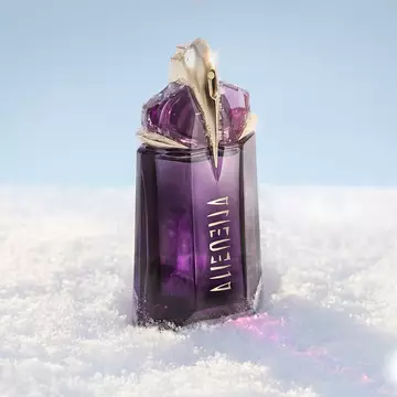 The signature deep purple, talisman-like Mugler Alien eau de parfum perfume bottle standing upright in a soft drift of white snow under bright, clean light.