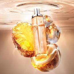 New Starlicious Pineapple Musk still life featuring the slender glass bottle surrounded by its key ingredients: a glowing pineapple slice, a cracked coconut shell, and crystalline musk, all set against a warm, luminous rippling water background.