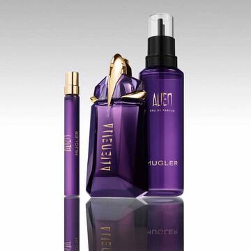 Mugler Alien perfume bottle with refill bottle and travel spray on reflective surface