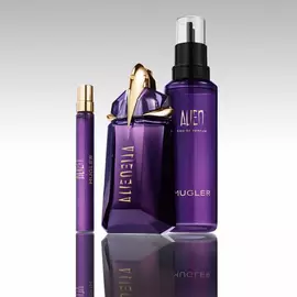 Mugler Alien perfume bottle with refill bottle and travel spray on reflective surface