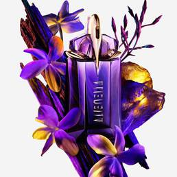 Mugler Alien perfume bottle surrounded by purple flowers and textured wood