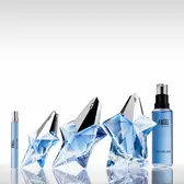 Angel Mugler travel spray, two blue star bottles, and refill bottle on a reflective surface