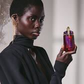 Model in black outfit holding Alien Hypersense perfume bottle