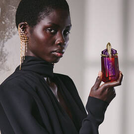 Model in black outfit holding Alien Hypersense perfume bottle