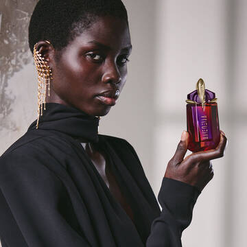 Model in black outfit holding Alien Hypersense perfume bottle