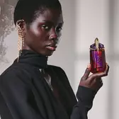 Model in black outfit holding Alien Hypersense perfume bottle
