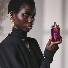 Model in black outfit holding Alien Hypersense perfume bottle