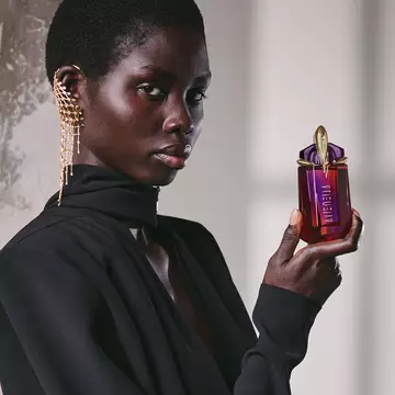Model in black outfit holding Alien Hypersense perfume bottle