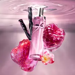 Starlicious Berry Licorice still life: slender glass bottle with strawberry, raspberry, fressia flower and black licorice sticks on a soft pink rippling water background.