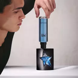 Man inserting A*Men Eau de Toilette blue refill bottle into black fragrance bottle.