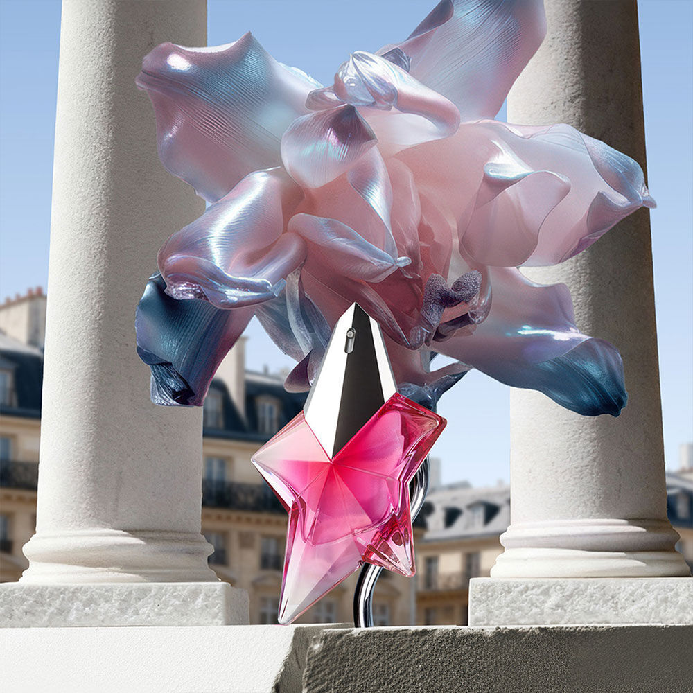 The Angel Nova pink star bottle standing on a Parisian stone balcony, framed by surrealist iridescent flowers and classical white pillars.