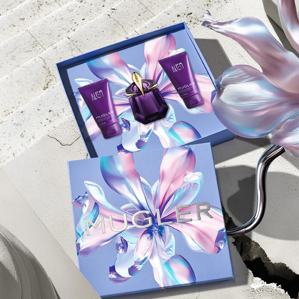 Opened Mugler Mother's Day 2026 gift box revealing an Alien Eau de Parfum set with a matching body lotion, and a shower gel against a sunlit Parisian stone backdrop