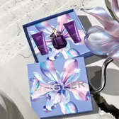 Opened Mugler Mother's Day 2026 gift box revealing an Alien Eau de Parfum set with a matching body lotion, and a shower gel against a sunlit Parisian stone backdrop