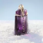 The signature deep purple, talisman-like Mugler Alien eau de parfum perfume bottle standing upright in a soft drift of white snow under bright, clean light.