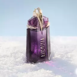 The signature deep purple, talisman-like Mugler Alien eau de parfum perfume bottle standing upright in a soft drift of white snow under bright, clean light.
