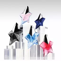 Five Mugler star perfume bottles in black, pink, blue, navy, and red on clear display blocks