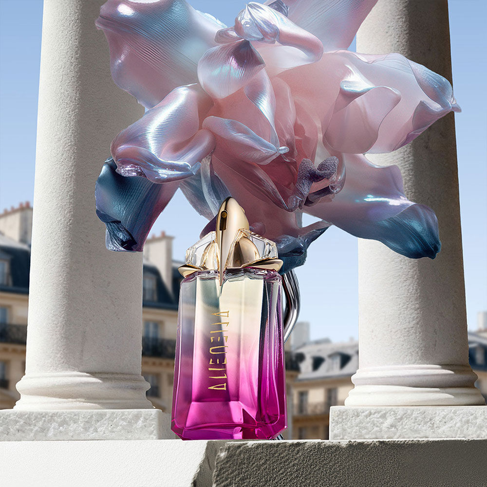 The Alien Pulp talisman bottle displayed between classical white pillars, accented by iridescent surrealist flowers and a bright sky.
