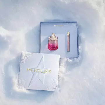 An open, textured ice-blue glistening Mugler gift set resting on snow, revealing an alien pulp eau de parfum 30 ml gift set