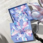 The Mugler Mother's Day 2026 gift box opened to reveal the Angel Eau de Parfum ritual set with blue body care tubes, presented on a sunlit stone surface.