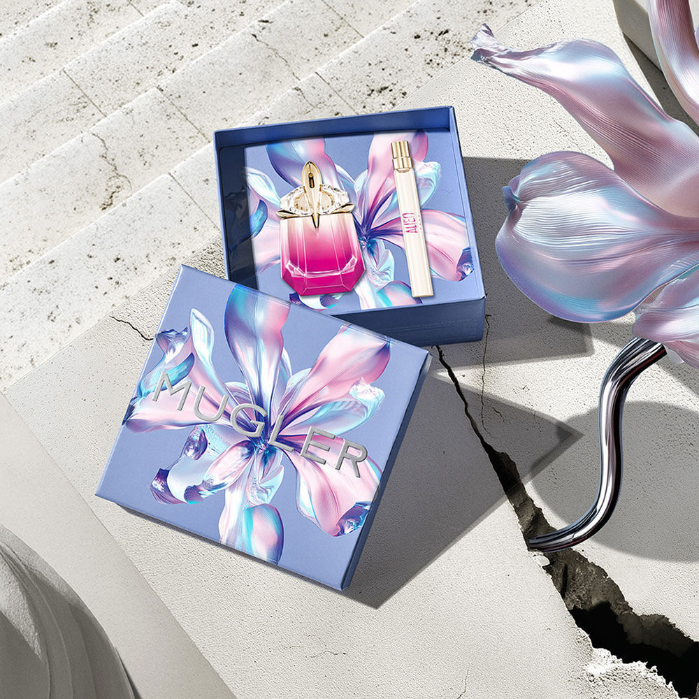 Mugler Mother's Day 2026 gift box with a kaleidoscopic floral pattern, containing the Alien Pulp perfume set on a sunlit stone surface with a concrete crack.