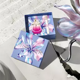 Mugler Mother's Day 2026 gift box with a kaleidoscopic floral pattern, containing the Alien Pulp perfume set on a sunlit stone surface with a concrete crack.