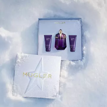An open, textured ice-blue glistening Mugler gift set resting on snow, revealing an alien eau de parfum 30ml gift set
