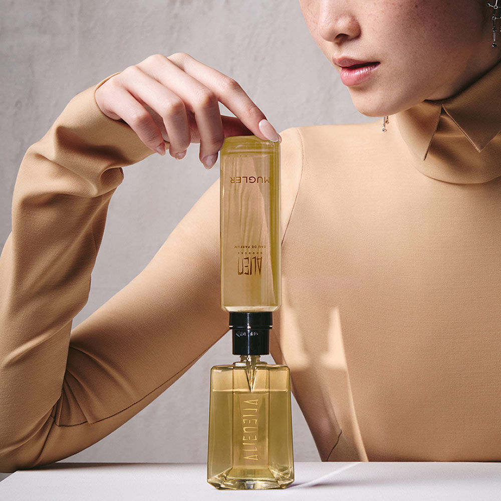 Model refilling an Alien Goddess perfume bottle with a matching refill bottle