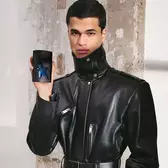Person holding black A*Men Mugler bottle against textured wall