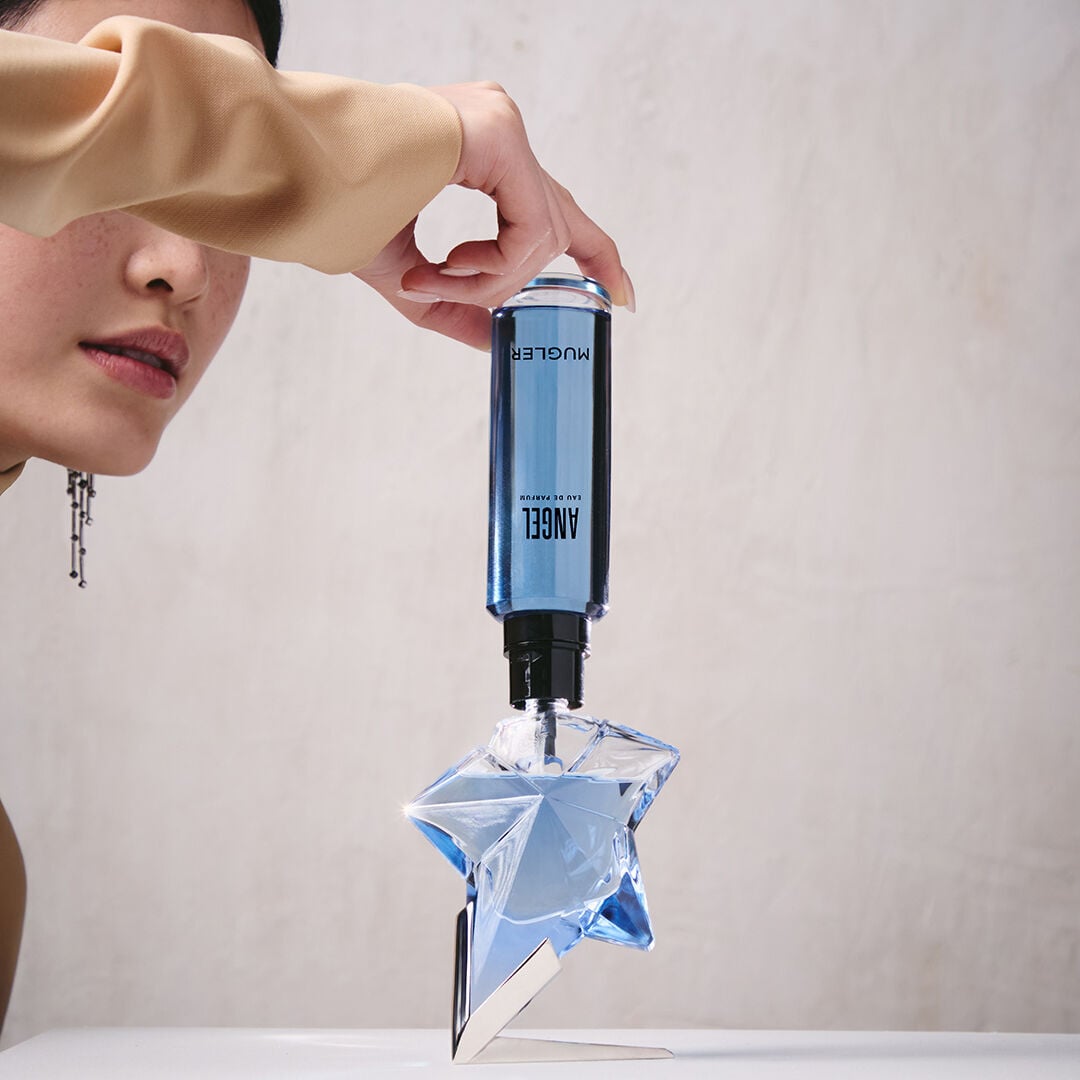 Refilling an Angel Mugler star perfume bottle with a blue refill bottle held upside down
