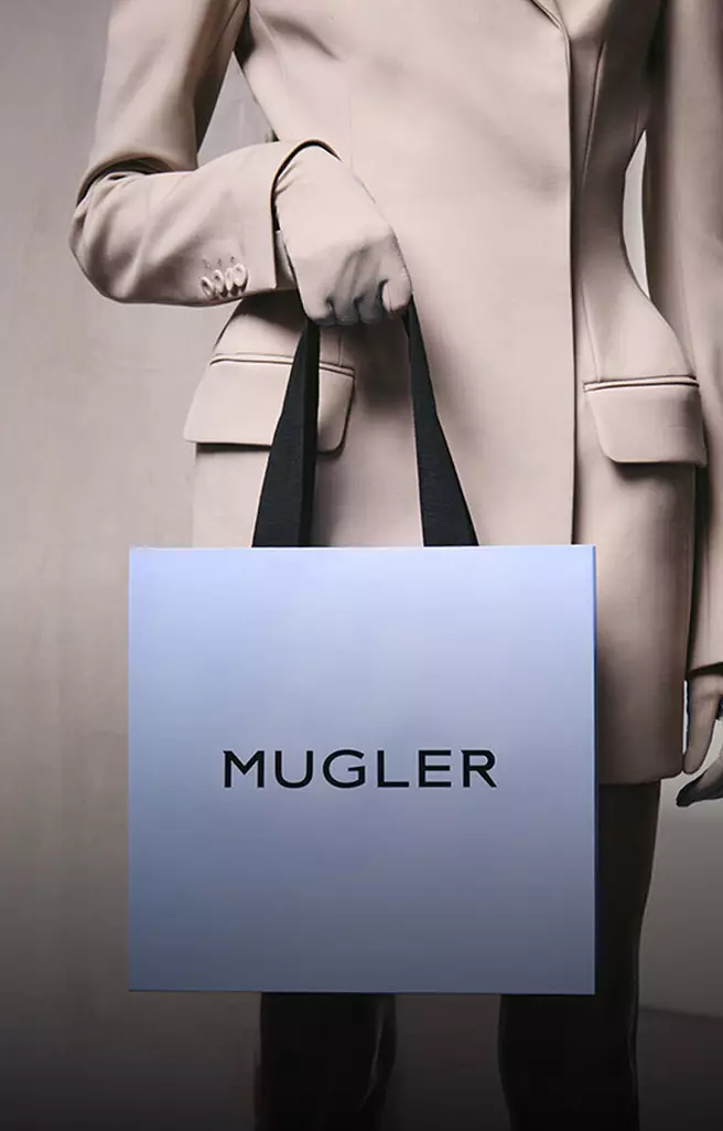 Model holding a Mugler shopping bag and promotional box for private sales and new launches.