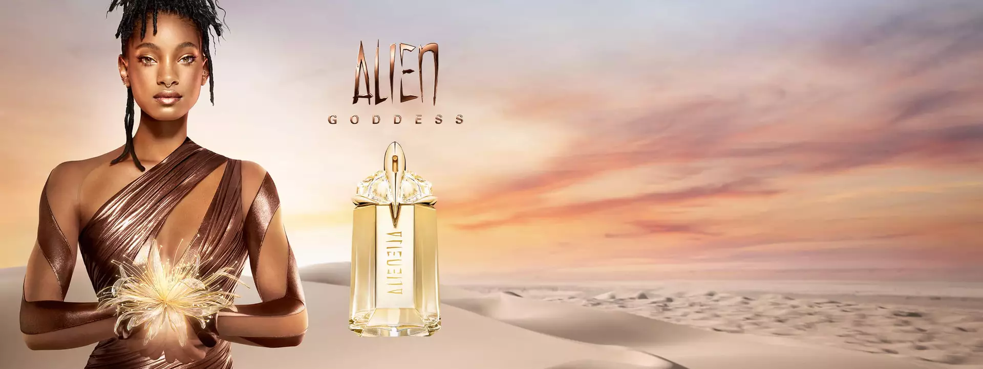 Willow Smith holding golden flower on a desert background in a bronze dress with Alien Goddess perfume