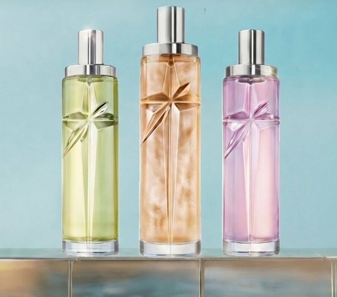 Three Starlicious Mugler refill bottles in green, amber and soft pink displayed on a tiled pool edge against a luminous blue background.