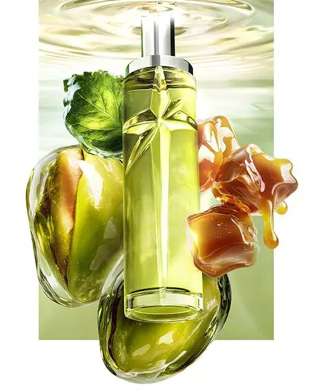 New Starlicious Pistachio Praline still life image featuring the slender bottle surrounded by its key ingredients: a patchouli leaf, whole pistachios, and dripping caramel cubes, all set against a luminous green rippling water background.