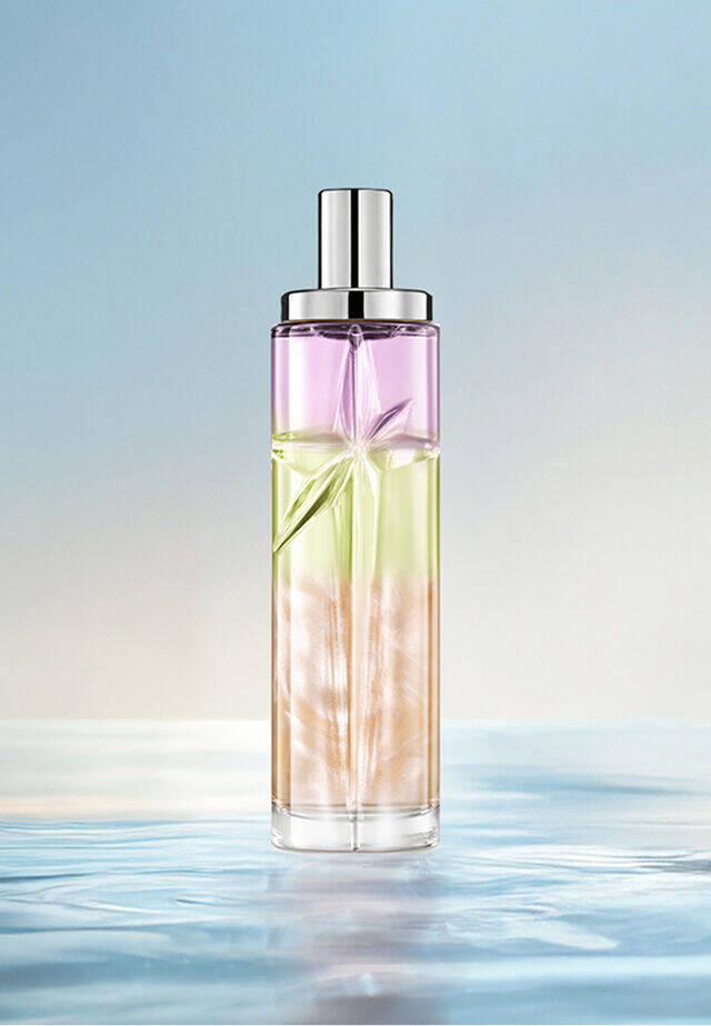 Yummy Swirl Starlicious layering recipe: tall bottle with purple, green and orange gradient on water against a soft blue background. Creamy, tropical, subtly nutty scent with a hint of berry; 2 sprays Pineapple Musk, 1 Pistachio Praline, 1 Berry Licorice.