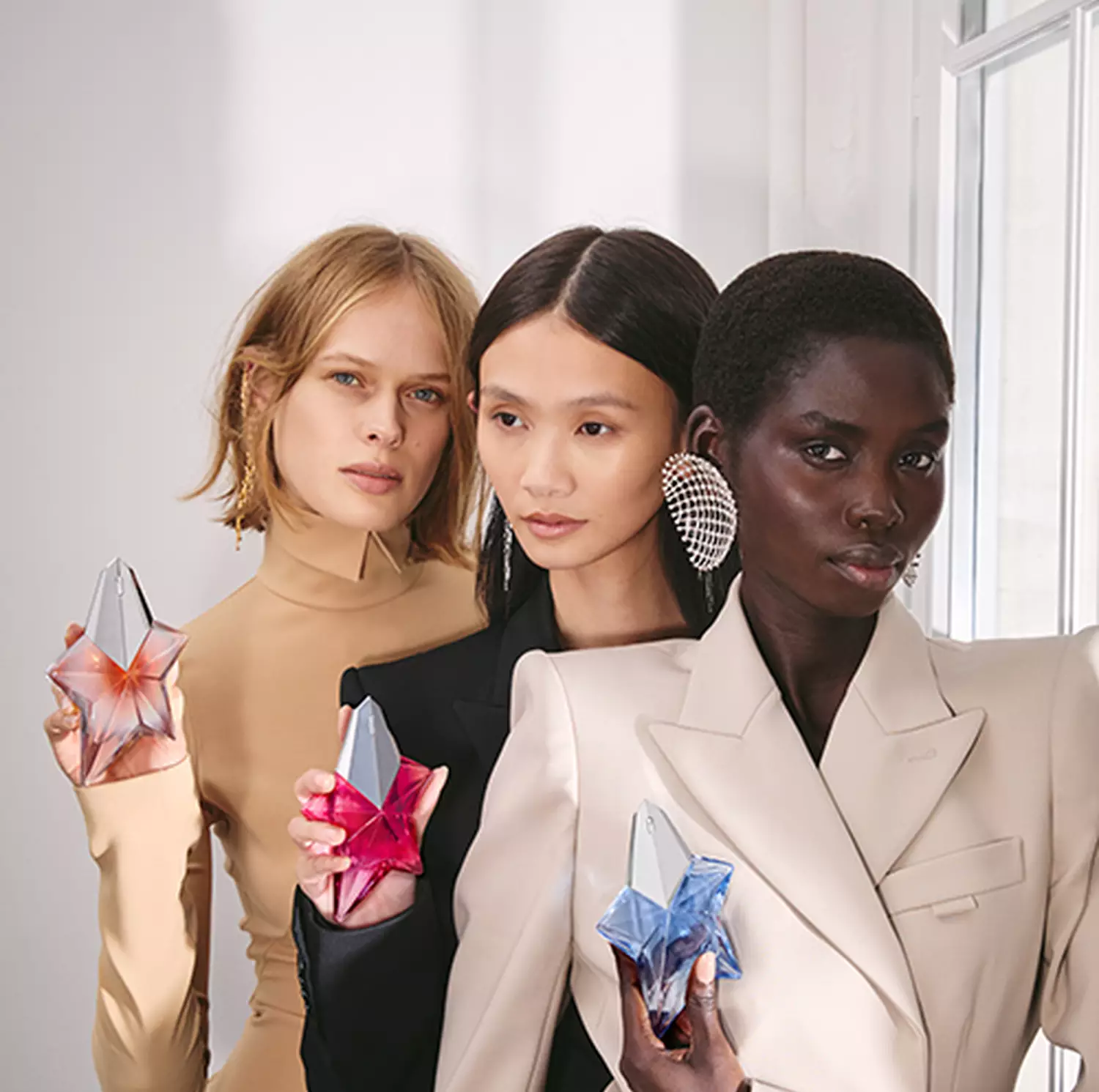 group of models holding mugler angel fragrance collection of engravable bottles