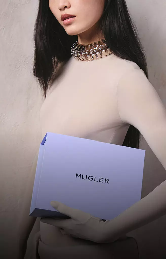 Model holding a Mugler gift box and loyalty envelope representing reward points per purchase.