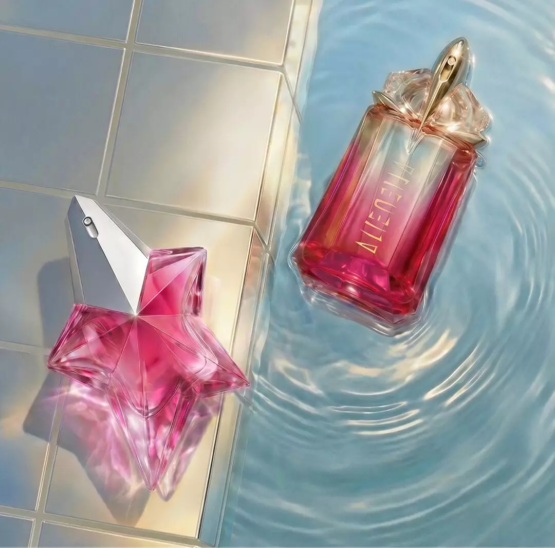 Pink Mugler Angel Nova star-shaped perfume bottle beside a pink gradient Mugler Alien Pulp bottle floating in rippling pool water next to glossy tiles.