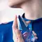 Zoomed in decolletage and hand holding Mugler Angel eau de parfum bottle