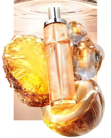 New Starlicious Pineapple Musk still life featuring the slender glass bottle surrounded by its key ingredients: a glowing pineapple slice, a cracked coconut shell, and crystalline musk, all set against a warm, luminous rippling water background.