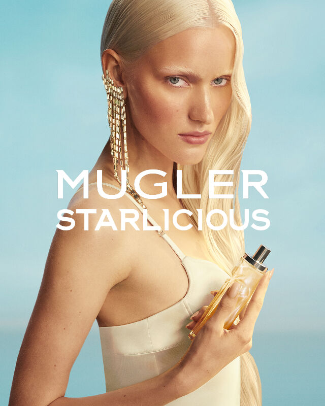 Mugler Starlicious Les Eaux Gourmandes campaign banner with model in pale yellow dress holding Pineapple Musk bottle against a soft blue sky.