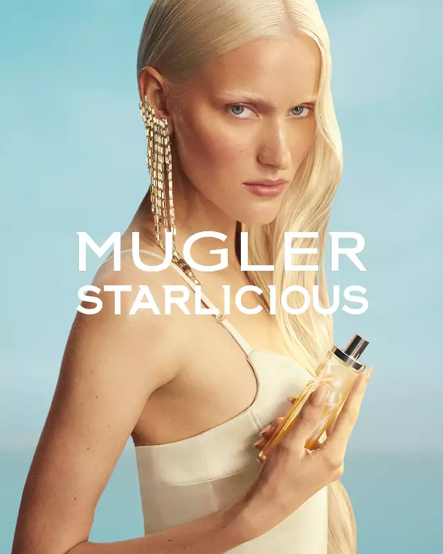 Mugler Starlicious Les Eaux Gourmandes campaign banner with model in pale yellow dress holding Pineapple Musk bottle against a soft blue sky.