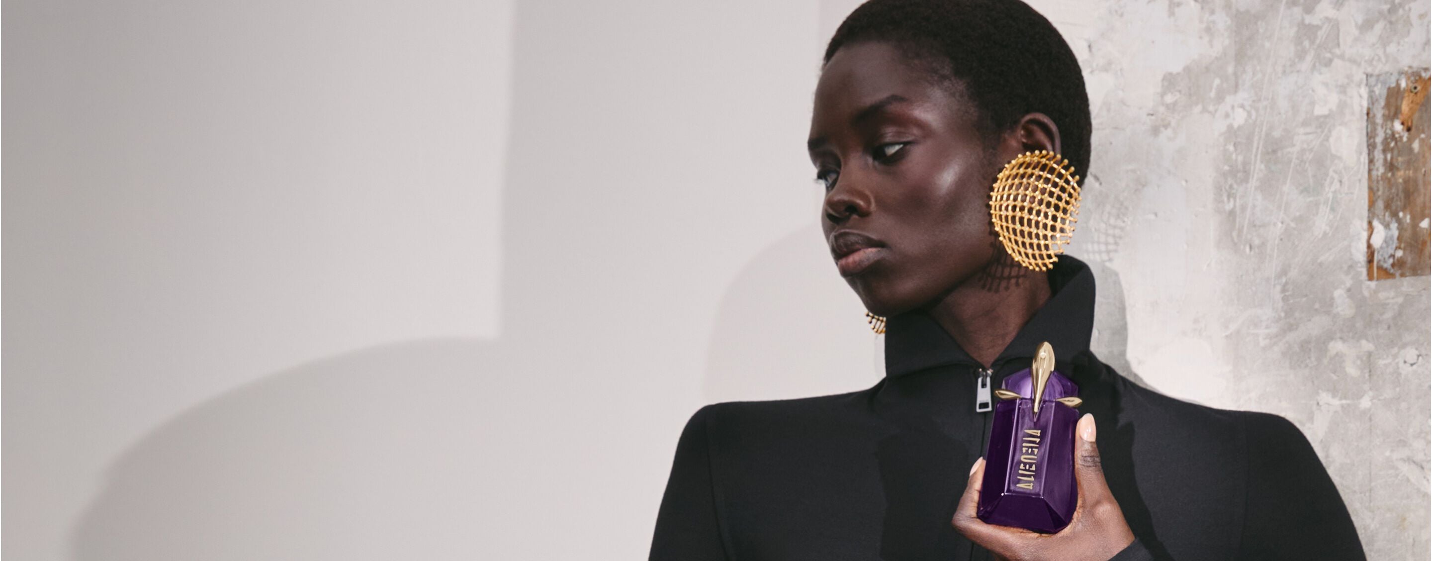 Model in black outfit holding Alien Hypersense perfume bottle