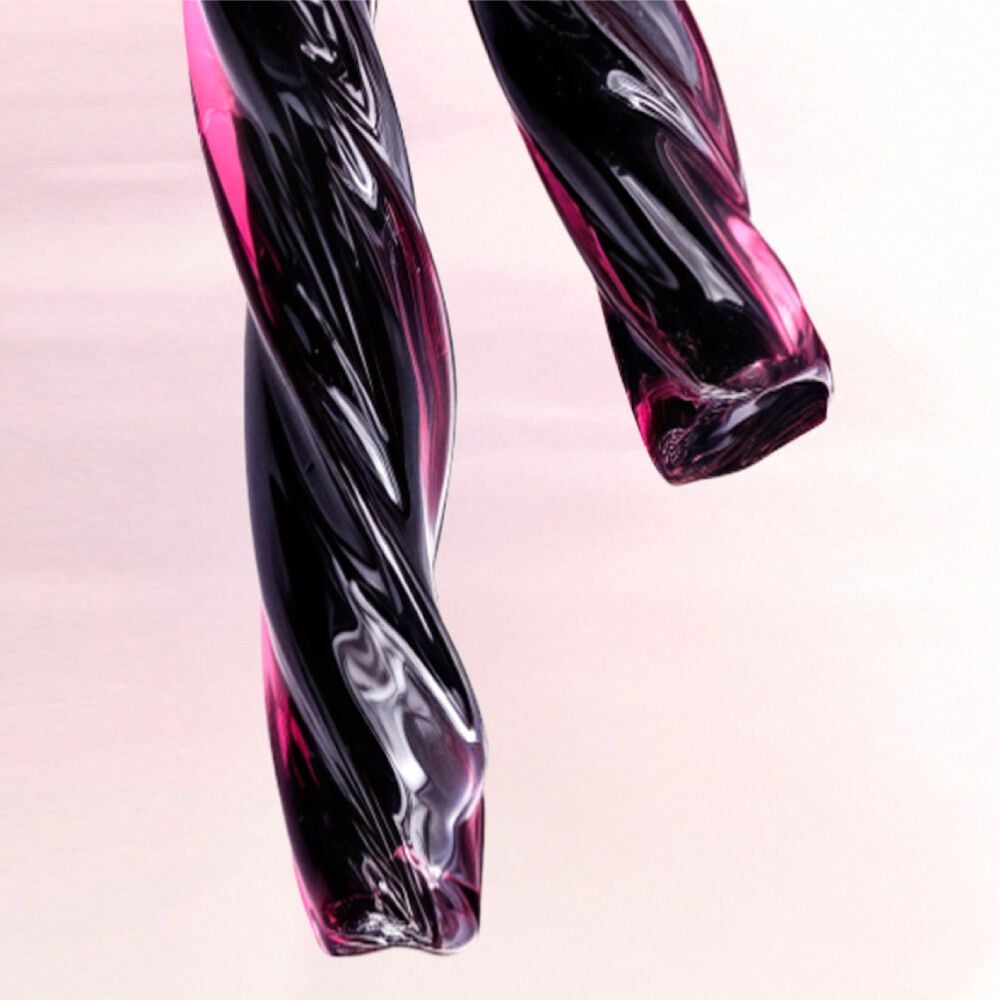 A close-up of two twisted, glossy strands of deep purple and black material resembling licorice. The text describes this as a deep licorice accord that adds contrast and intensity, anchoring the composition of the scent.